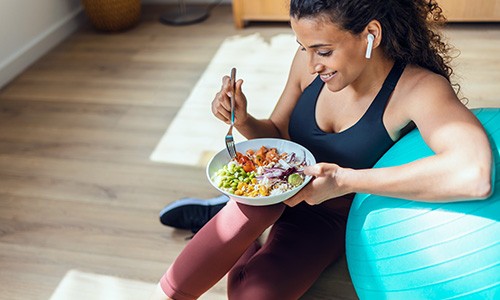 Closeup of woman smiling while eating post-workout meal